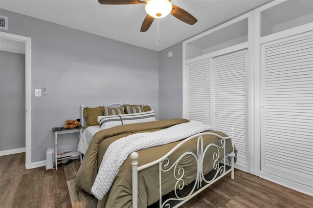 bedroom with a ceiling fan, visible vents, wood finished floors, and baseboards