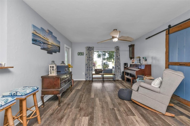 sitting room with baseboards, a ceiling fan, a barn door, and wood finished floors