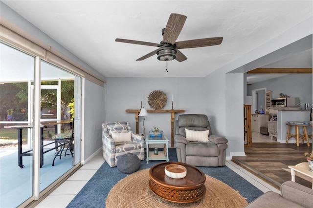 living area featuring tile patterned floors, baseboards, and ceiling fan