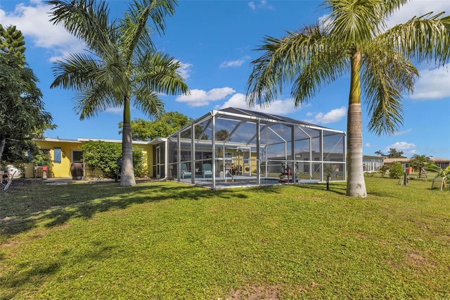 rear view of property with glass enclosure, a yard, and an outdoor pool