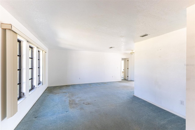 carpeted empty room featuring visible vents and a textured ceiling