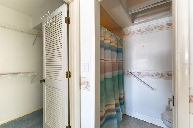 bathroom featuring tile patterned floors, baseboards, toilet, a shower with curtain, and a closet