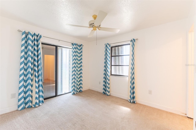 carpeted empty room with a ceiling fan, baseboards, and a textured ceiling