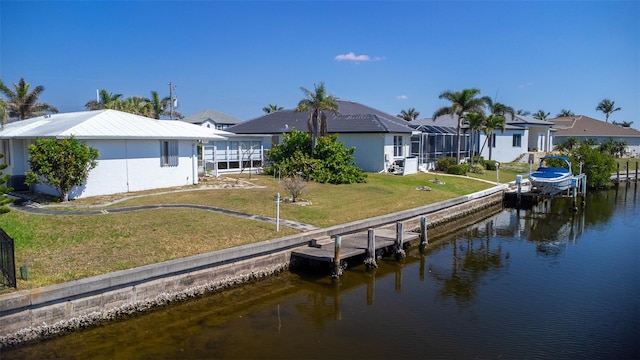 view of dock with glass enclosure, a yard, a water view, boat lift, and a residential view