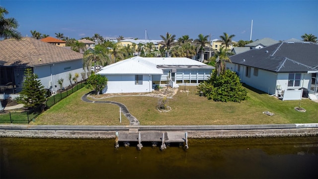 back of property with fence, a lawn, a water view, and a residential view