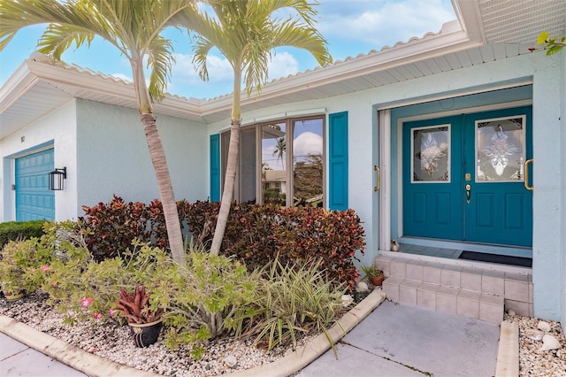 entrance to property featuring an attached garage and stucco siding