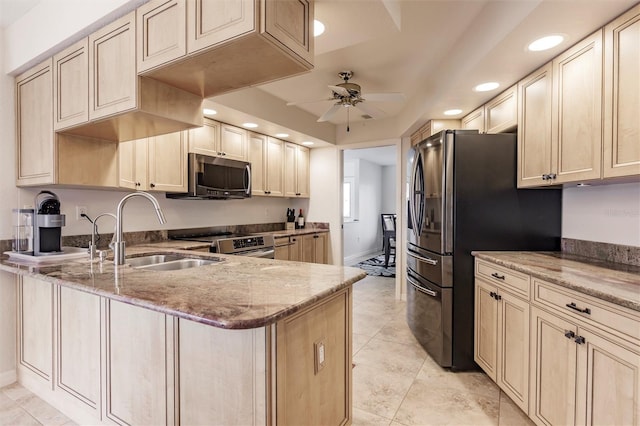 kitchen featuring light stone countertops, a peninsula, ceiling fan, a sink, and appliances with stainless steel finishes