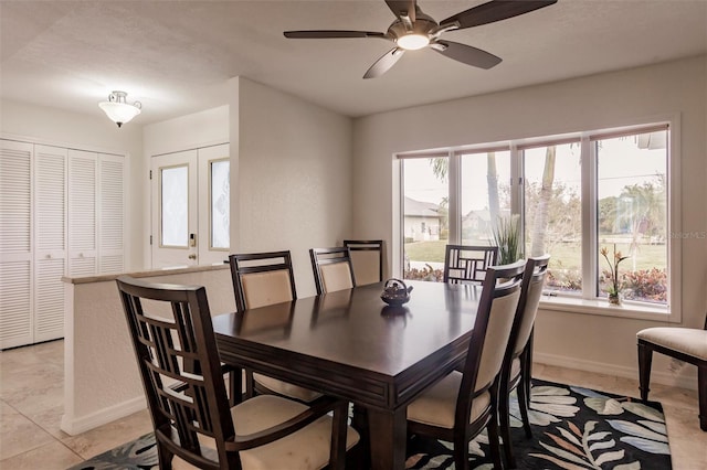 dining space with light tile patterned flooring, a ceiling fan, and baseboards