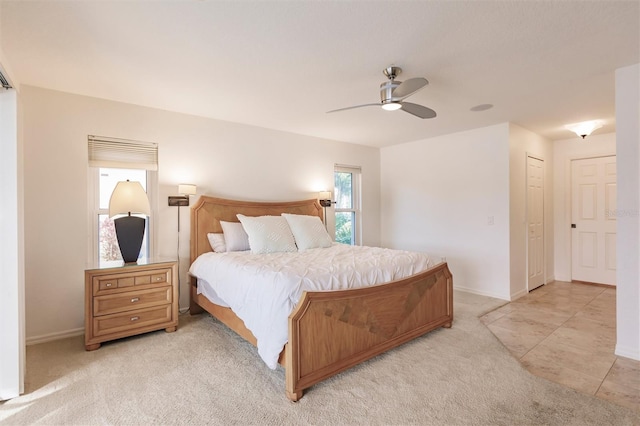 bedroom featuring light tile patterned flooring, light colored carpet, baseboards, and ceiling fan