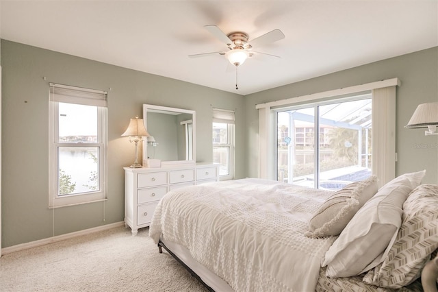 bedroom featuring multiple windows, light colored carpet, baseboards, and access to outside