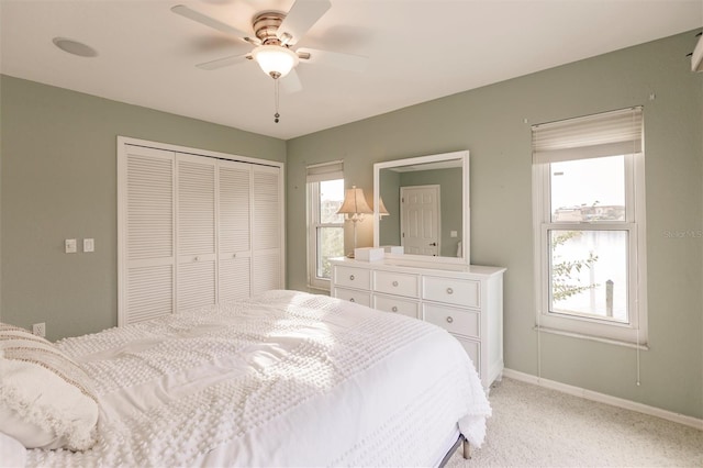 bedroom featuring multiple windows, light colored carpet, a closet, and baseboards