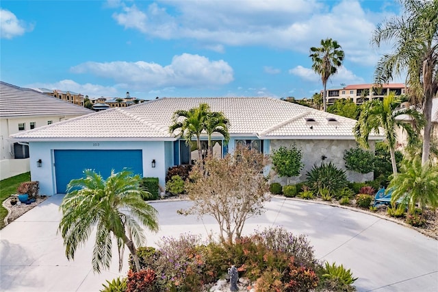 view of front of home with a tile roof, concrete driveway, a garage, and stucco siding