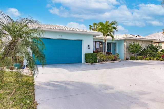 ranch-style house with stucco siding, a garage, driveway, and a tiled roof