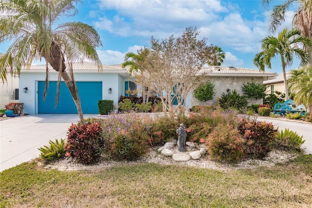 view of front of property featuring stucco siding, a tiled roof, concrete driveway, and a garage