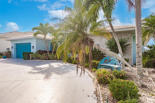 view of front of house featuring concrete driveway, a tiled roof, an attached garage, and stucco siding