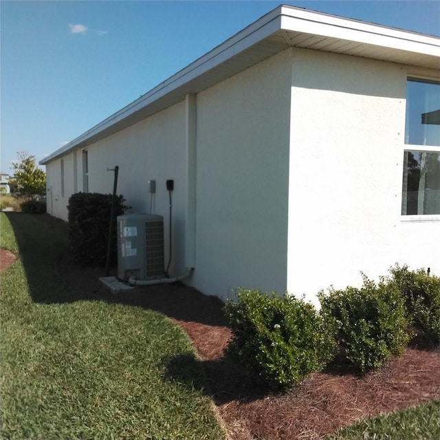 view of home's exterior with cooling unit, a yard, and stucco siding