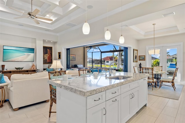 kitchen featuring a sink, a raised ceiling, open floor plan, and ceiling fan