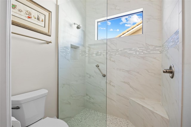 full bathroom featuring tiled shower and toilet