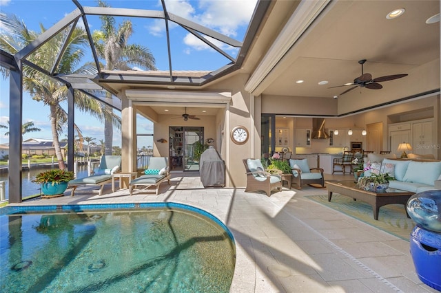 outdoor pool with a ceiling fan, glass enclosure, a patio area, and an outdoor hangout area