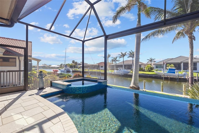 view of swimming pool with glass enclosure, a patio, a water view, and a pool with connected hot tub