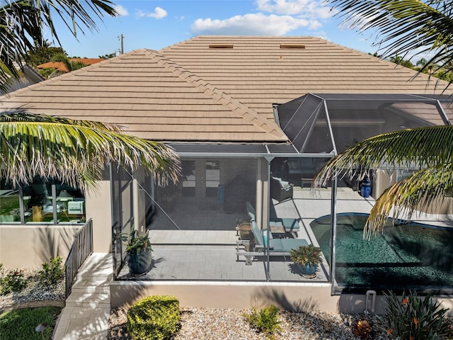 rear view of property featuring a tile roof, a lanai, and a patio area
