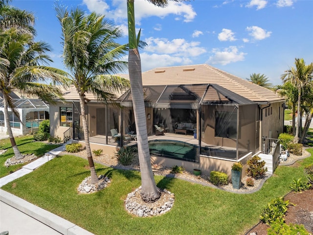 back of property with a patio, a yard, an outdoor pool, and a lanai