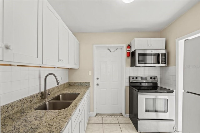 kitchen with light stone counters, a sink, white cabinets, appliances with stainless steel finishes, and backsplash