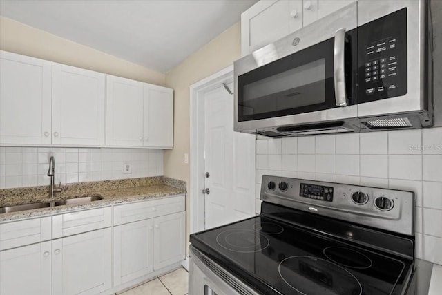 kitchen featuring a sink, light stone counters, stainless steel appliances, white cabinets, and decorative backsplash