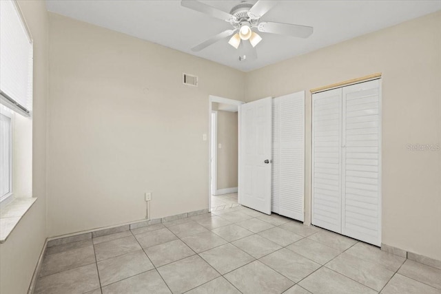 unfurnished bedroom with a closet, visible vents, a ceiling fan, and light tile patterned floors