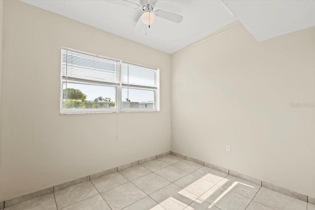 empty room with light tile patterned floors, baseboards, and a ceiling fan