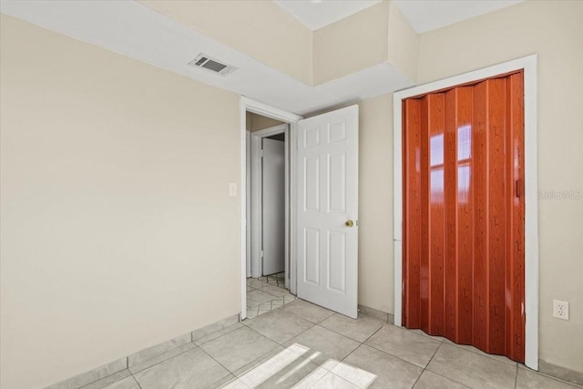 unfurnished bedroom with light tile patterned flooring, visible vents, and a closet