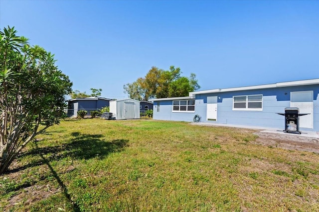 back of property featuring a storage shed, a yard, and an outdoor structure