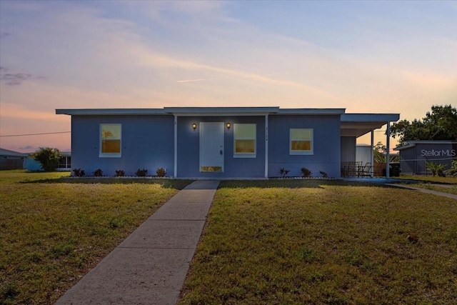 view of front of home with an attached carport and a yard