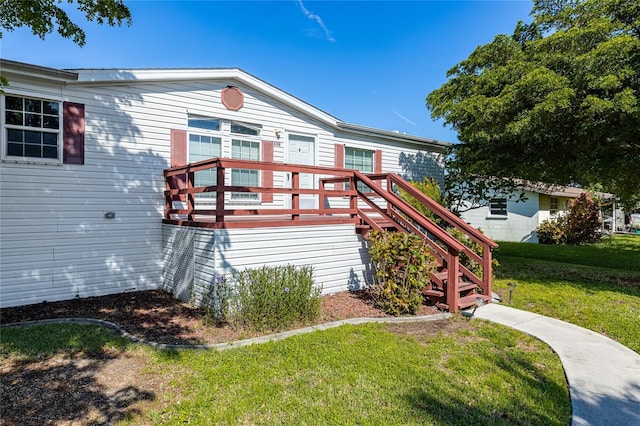 back of property with a deck, a yard, and stairs