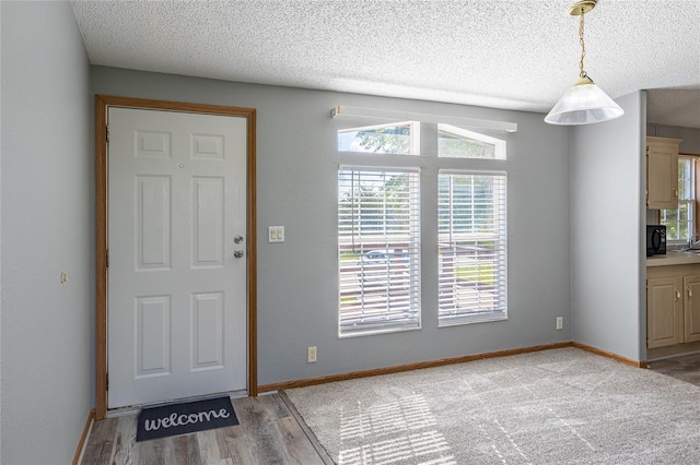 foyer featuring light wood-type flooring, baseboards, and a textured ceiling