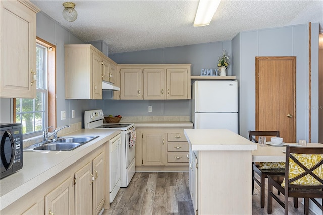 kitchen with white appliances, a kitchen island, light countertops, and a sink