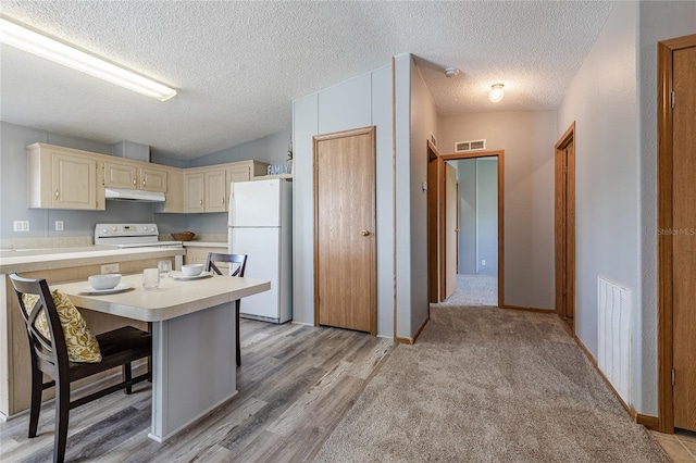 kitchen featuring under cabinet range hood, visible vents, white appliances, and light countertops