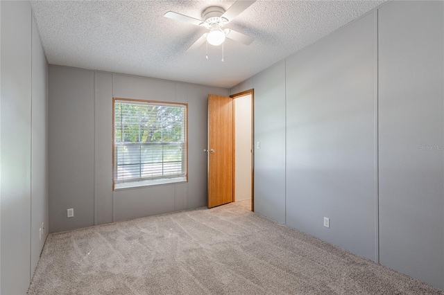 carpeted spare room with a textured ceiling and a ceiling fan