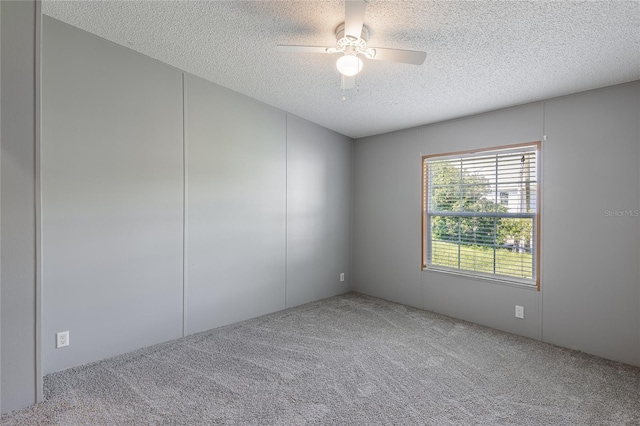 carpeted spare room with a textured ceiling and ceiling fan