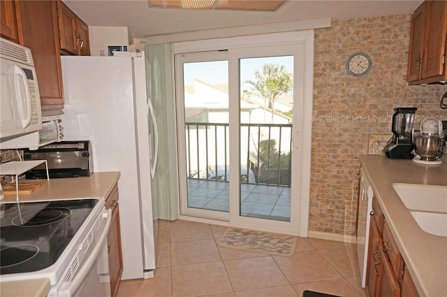 kitchen with light tile patterned floors, brown cabinets, white appliances, and light countertops