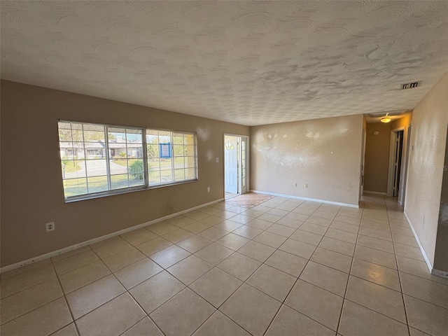 spare room with light tile patterned floors, baseboards, visible vents, and a textured ceiling