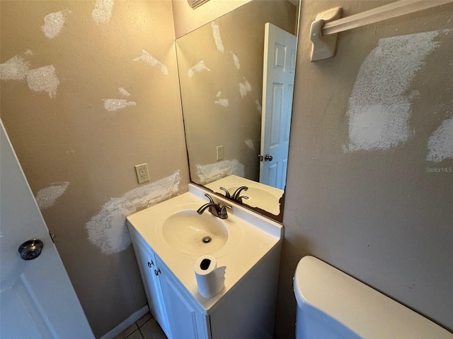 half bathroom featuring tile patterned floors, toilet, and vanity