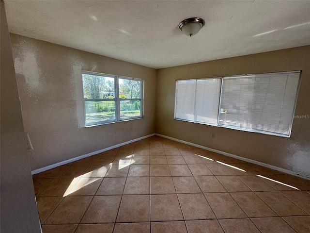 empty room with baseboards and tile patterned flooring