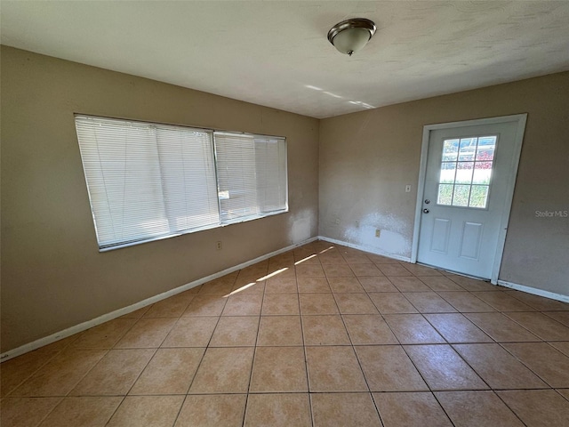 empty room with light tile patterned flooring and baseboards