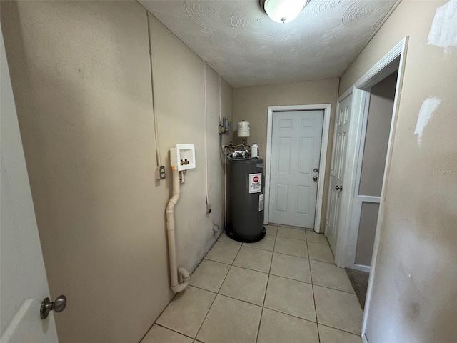 hall featuring light tile patterned flooring, water heater, and a textured ceiling