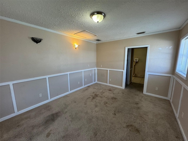 carpeted empty room with crown molding, a decorative wall, visible vents, and a textured ceiling