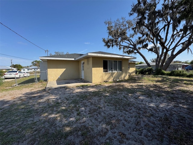 back of property featuring stucco siding and fence