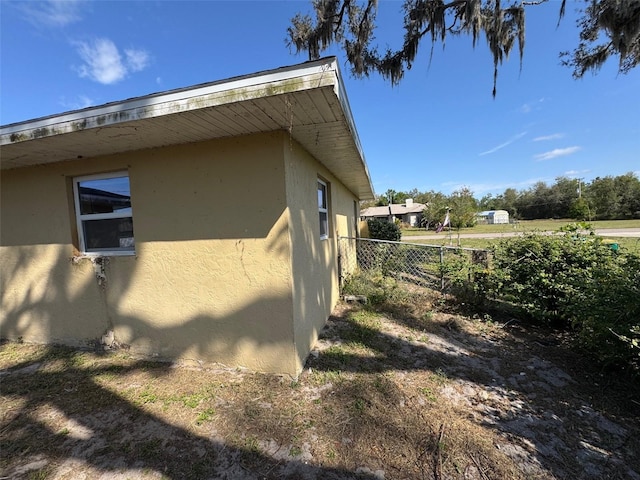 view of home's exterior with stucco siding and fence