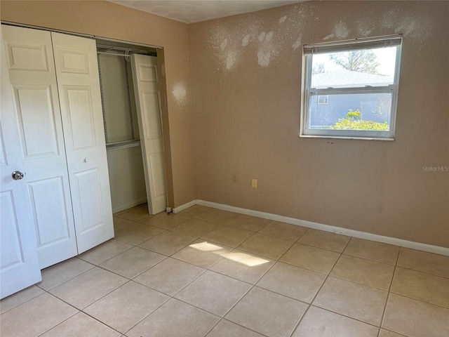 30147 Holly Rd, Punta Gorda, FL 33982 - unfurnished bedroom featuring light tile patterned flooring, baseboards, and a closet