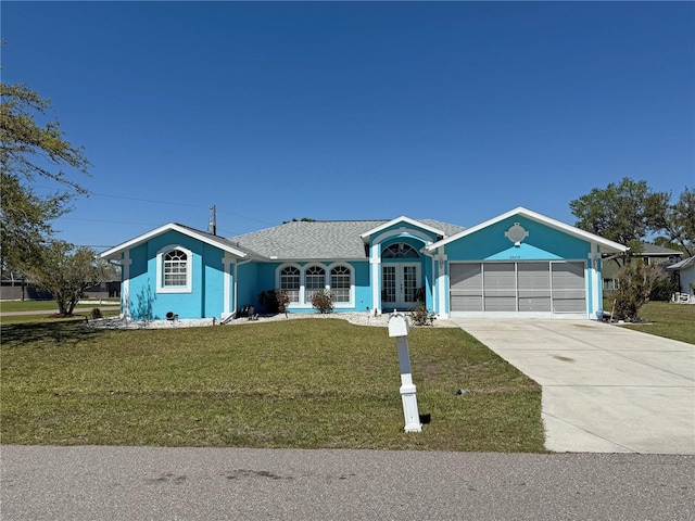 ranch-style house with a front lawn, an attached garage, french doors, and driveway